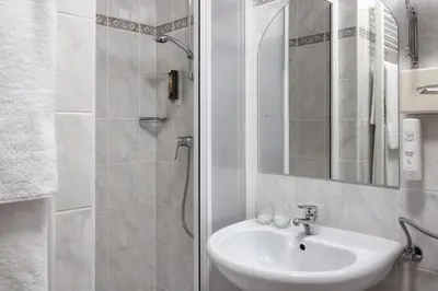 a white bathroom with a sink and a shower at Hotel Kompas in Bled