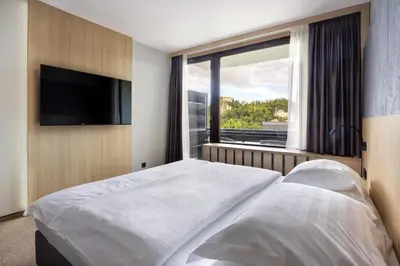 a bedroom with a bed and a large window at Hotel Kompas in Bled