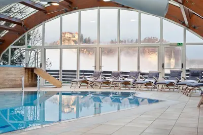 a pool with chairs in a large room with windows at Hotel Kompas in Bled