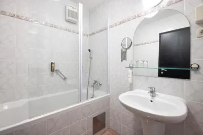 a white bathroom with a sink and a shower at Hotel Kompas in Bled