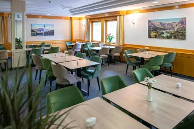 a restaurant with wooden tables and green chairs at Hotel Jezero in Bohinj