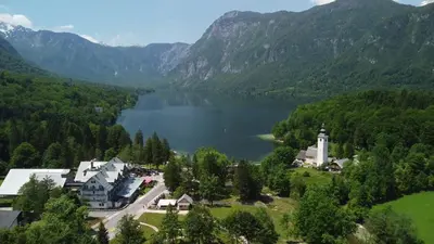 arial view of a lake and a town with a church at Hotel Jezero in Bohinj