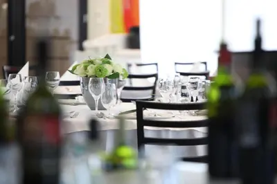 a table with glasses and a vase of flowers on it at M Hotel in Ljubljana