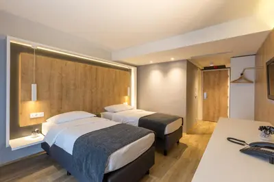 a hotel room with two beds and a desk at M Hotel in Ljubljana