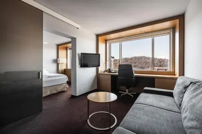 a hotel room with a couch and a bed and a window at Exe Lev in Ljubljana