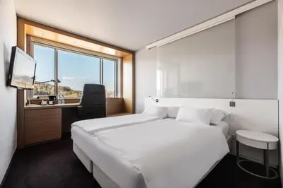 a bedroom with a white bed and a desk and a window at Exe Lev in Ljubljana
