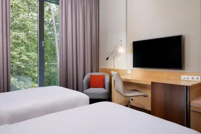 a hotel room with a bed and a desk and a tv at Four Points by Sheraton Ljubljana Mons in Ljubljana