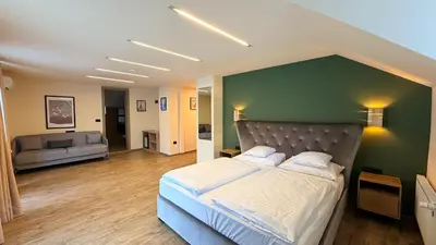 a bedroom with a large bed with a green wall at Hotel Kranjska Gora in Kranjska Gora