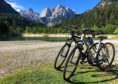 two bikes parked next to a river and mountains at Hotel Kranjska Gora in Kranjska Gora