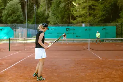 a woman holding a tennis racket on a tennis court at Hotel Kranjska Gora in Kranjska Gora