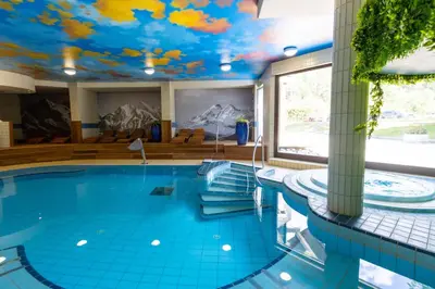 a swimming pool with a mural of clouds on the ceiling at Hotel Kranjska Gora in Kranjska Gora