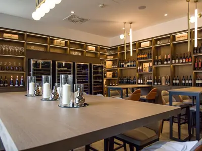 a dining room with a large table and shelves of wine bottles at Elegans Hotel Brdo in Kranj