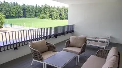 a balcony with chairs and tables and a large window at Elegans Hotel Brdo in Kranj