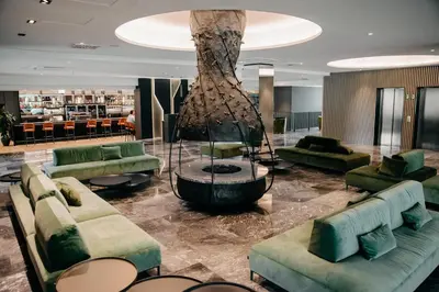 a lobby with green couches and a tree at Elegans Hotel Brdo in Kranj