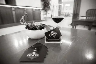 a glass of wine sitting on a table next to a bowl of plants at ECO Hotel Center Postojna in Postojna