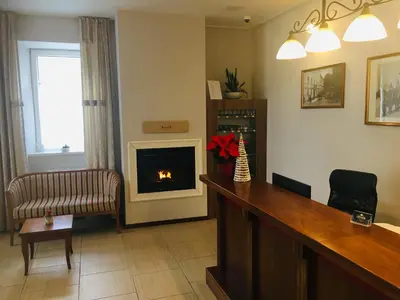 a living room with a fireplace and a desk with a bar at ECO Hotel Center Postojna in Postojna