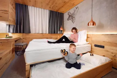 a woman and a child sitting on two beds at Rogla – Hotel Rogla in Resnik