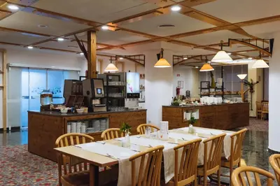 a restaurant with a table and chairs and a kitchen at Rogla – Hotel Rogla in Resnik