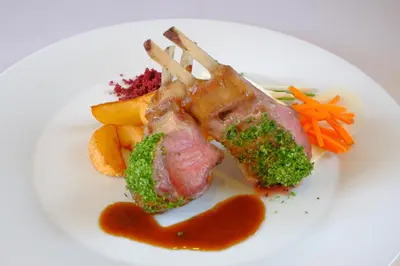 a white plate with a piece of meat and vegetables at Rogla – Hotel Rogla in Resnik