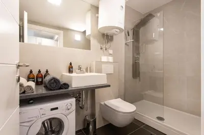 a bathroom with a toilet a sink and a washing machine at Urban Style Apartments by Loft in Ljubljana