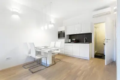 a white kitchen with a table and white chairs at Urban Style Apartments by Loft in Ljubljana