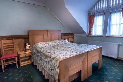 a bedroom with a bed and a chair and windows at Hotel in restavracija Pod Roglo in Zreče
