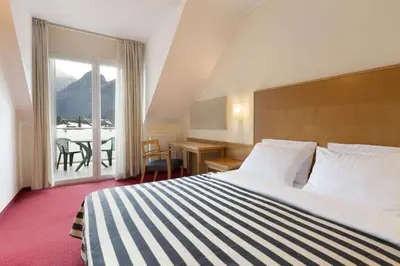 a hotel room with a bed and a view of a table at Ramada Hotel & Suites Kranjska Gora in Kranjska Gora