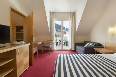 a hotel room with a bed and a couch at Ramada Hotel & Suites Kranjska Gora in Kranjska Gora