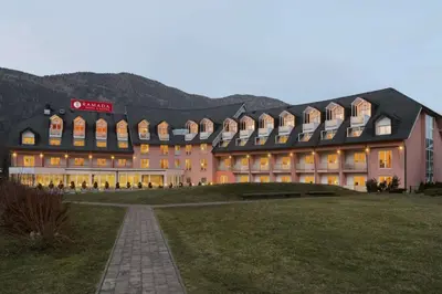 a large building with a mountain in the background at Ramada Hotel & Suites Kranjska Gora in Kranjska Gora