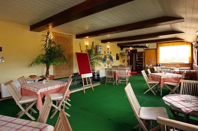 a restaurant with tables and chairs and a green floor at Pri Ancki Sobe Rooms Accomodation Ljubljana suburbs in Medvode