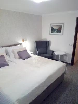 a bedroom with a large white bed and a chair at Sport Manca Garni Hotel in Radovljica