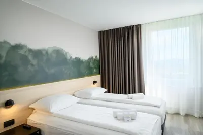 two beds in a hotel room with a window at B&B Hotel Ljubljana Park in Ljubljana