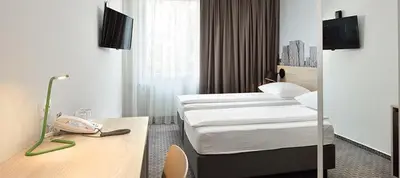 a hotel room with two beds and a phone on a desk at B&B Hotel Ljubljana Park in Ljubljana