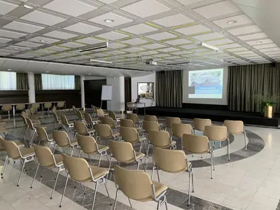 a room with rows of chairs and a projection screen at Hotel Alp in Bovec