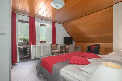 a bedroom with a large bed with a red blanket at Garni Hotel Miklič in Kranjska Gora