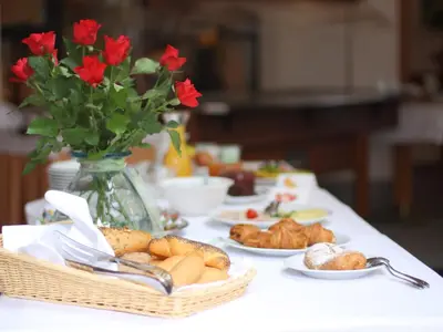 a table with plates of food and a vase of flowers at Garni Hotel Miklič in Kranjska Gora