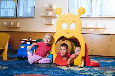 two children playing in a play structure in a nursery at Hotel Planja in Zreče