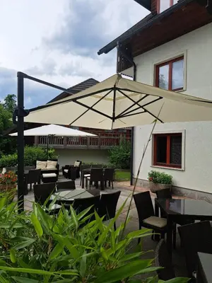 a patio with tables and chairs and an umbrella at Aparthotel Gaja in Bled