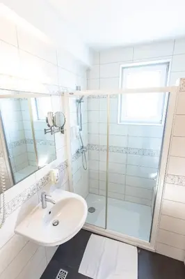 a bathroom with a sink and a shower at Hotel Bau Maribor in Maribor
