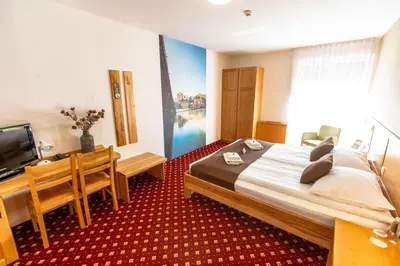 a bedroom with a bed and a desk and a television at Hotel Bau Maribor in Maribor