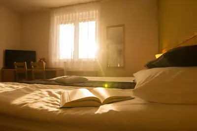 an open book laying on a bed with a window at Hotel Bau Maribor in Maribor