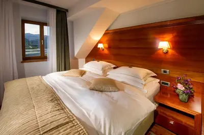 a bedroom with a large white bed with a wooden headboard at Hotel Lovec in Bled