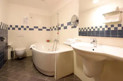 a bathroom with a tub and a sink and a toilet at Hotel Lovec in Bled