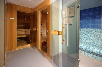 a walk in shower in a bathroom with blue tiles at Hotel Lovec in Bled