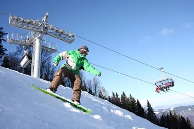 a man riding a snowboard down a snow covered slope at Hotel Tabor Maribor in Maribor