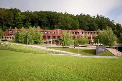 a large red building with a park in front of it at Terme Olimia - Hotel Sotelia in Podčetrtek
