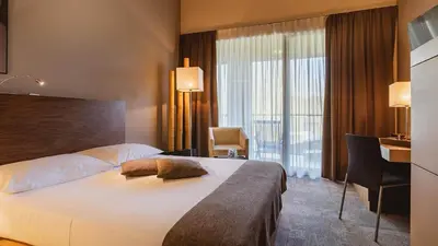 a hotel room with a large bed and a desk at Terme Olimia - Hotel Sotelia in Podčetrtek