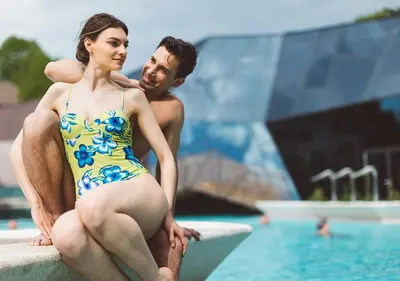 a man and a woman in a swimsuit sitting next to a pool at Terme Olimia - Hotel Sotelia in Podčetrtek