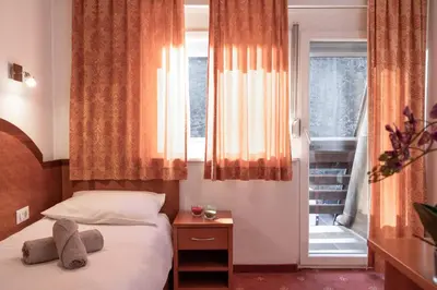 a small bedroom with a bed and a window at Hotel Medno in Ljubljana