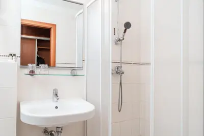 a white bathroom with a sink and a shower at Hotel Medno in Ljubljana